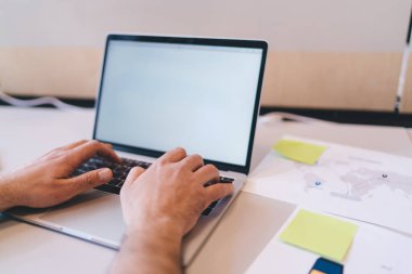 Ofiste proje üzerinde çalışırken boş ekranla dizüstü bilgisayarın klavyesine yazı yazan yüzü olmayan erkek girişimci