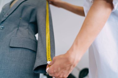 Günümüz atölyesinde çalışırken sıradan bir kadın terzi ceketinin kolunun ölçüsünü alıyor.