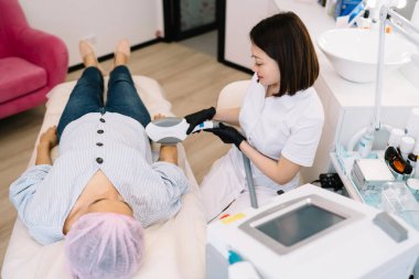 Yüksek açılı kadın üniforma uzmanı sandalyede oturuyor ve iş sırasında özel ekipmanlarla ultrason kaldırma işlemi yapıyor.