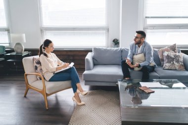 Odaklanmış kadın terapistin yazışmalarına ve rahat koltukta oturup depresyondan bahseden sakallı erkek müşteriyi dinlemesine ek bakış açısı