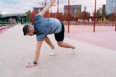 Modern şehrin yakınlarındaki stadyumdaki spor sahasında spor yaparken spor yaparken spor yapan aktif giyimli güçlü sporcu ve akıllı saat.