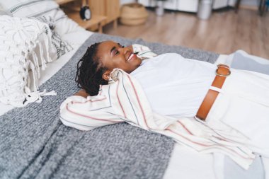 Afro örgülü, çizgili gömlekli, yumuşak yastıklı ve kapalı gözlü Afro-Amerikan kadının yüksek açısı.