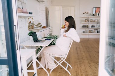 Yan bakışta, bebek koltuğunun arkasına yaslanırken masada dinlenirken dizüstü bilgisayarda film seyrederken sağlıklı atıştırmalıklar yerken görülüyor.