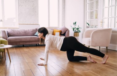 Side view full body of concentrated woman stretching legs while practicing prenatal yoga doing Chakravakasana exercise balancing and preparing body for childbearing clipart