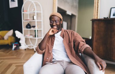 Cep telefonlu içerik sahibi Afro-Amerikan erkek. İzinli günlerinde oturma odasındaki rahat koltukta dinlenirken başka tarafa bakıyor ve derin derin düşünüyor.