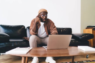 Masanın yanındaki deri koltukta oturan ve dizüstü bilgisayar kullanarak projede çalışan şık giysili serbest çalışan sakallı adam hayrete düştü.