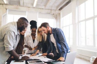 Genç ve çok ırklı kadın ve erkek gruplarının gazetelerle masada toplanıp ofiste projenin detaylarını tartışarak yeni bir başlangıç yapmaları ilham verici.
