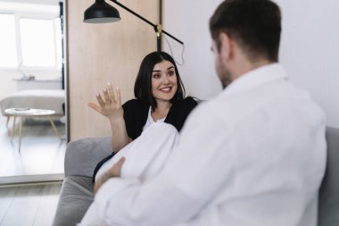 Harika bir eş kocasıyla konuşuyor ve birbirine bakarken el kol hareketi yapıyor ve hafta sonları geniş yatak odasında rahat bir kanepede dinleniyor.