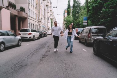 Şehirdeki randevularında günlük giysiler içinde el ele tutuşan ve yolda koşan neşeli genç erkek ve kadınların tüm vücudu.