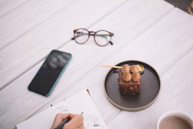 Kafeterya masasında nefis çikolatalı pasta, pastane, stil konsepti ve kafeteryada yemek sanatı ile çizim yapan tanınmamış kadın tasarımcı görüntüsü.
