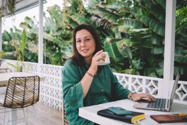 Uzaktan kumandalı balkonda çalışmak için kameraya bakan yetenekli kadın bilişim uzmanı portresi. Modern dizüstü bilgisayarlı, web ağı pozu veren bir kadın.