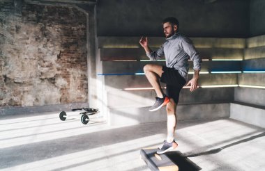 Aerobik basamaklarda erkek sporcuların antrenmanlarının yan görüntüsü ve sabahları geniş spor stüdyosunda spor yaparken bakışlarını başka yöne çevirmeleri.