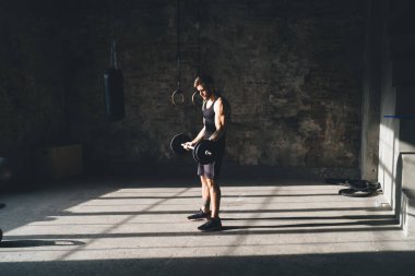 Modern fitness merkezinde antrenman yaparken ağırlık kaldıran güçlü erkek sporculardan oluşan bir yan görüş.