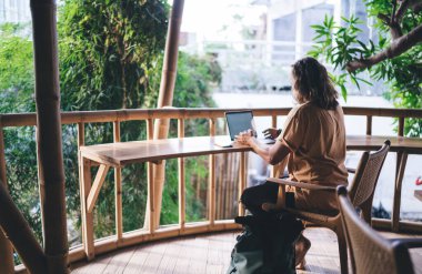 Uzun saçlı yazılım geliştirici çevrimiçi veri programlama için dizüstü bilgisayar uygulaması kullanıyor, yetenekli erkek bilişim uzmanı terasta kablosuz tarayıcı ağı kurmak için dijital netbook üzerine medya uygulaması yüklüyor