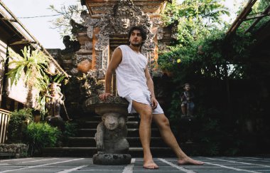 Endonezya 'daki Budist Ubud Pura Taman Saraswati Tapınağı' na karşı otururken manzaranın tadını çıkaran erkek turistlerin zemin seviyesi