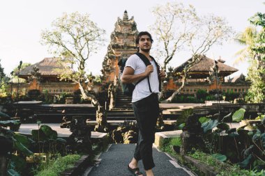 Endonezya 'daki Ubuds Pura Taman Saraswati Tapınağı' nın yakınlarındaki tropikal bahçeye hayran olan erkek etnik turistin aşağısından.