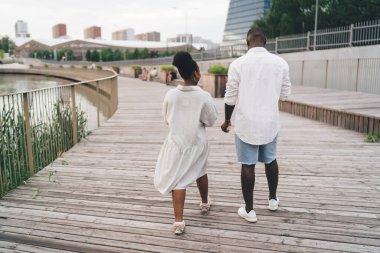 Genç Afro-Amerikan çiftin gündelik kıyafetleriyle ahşap set boyunca yürümelerini ve yazın şehirde keyifli bir hafta sonu geçirmelerini izliyoruz.