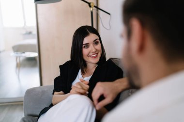 Sevgilisini dinleyen, gülümseyen, birbirine bakan ve hafta sonları rahat bir kanepede dinlenen bir kız arkadaş.
