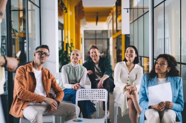 Bir grup çok ırklı iş arkadaşı iş yerinde oturup proje detaylarını tartışırken, aynı zamanda birbirleriyle toplantı sırasında başlangıçta çalışırlar.