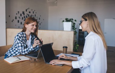 Gülümseyen çalışanlar gündelik kıyafet ve dizüstü bilgisayarlarla cep telefonuyla fikirleri paylaşırken aynı zamanda geniş ofislerde başarılı bir proje üzerinde çalışıyorlar.