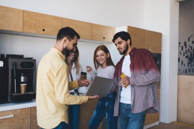 Ofisteki yeni iş projesinden bahsederken günlük giysiler içinde gülümseyen ve netbook ekranına bakan mutlu genç iş arkadaşları.