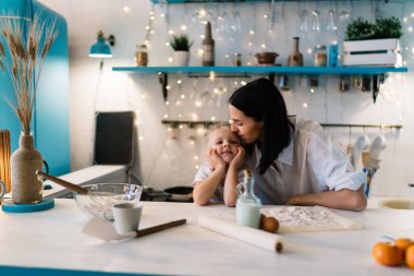 Mutluluk dolu genç bir kadın, el ele tutuşup sarılıyor ve öpüyor. Bu sırada tezgahta elinde malzemelerle oturuyor ve mutfakta birlikte kahvaltı hazırlıyor.