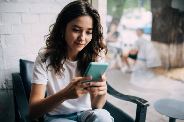 Sosyal ağ kurmak ve sosyal medyada sohbet etmek için cep telefonu teknolojisini kullanan beyaz kadın blogcu, akıllı telefon cihazlı bin yıllık kadın mobil uygulama üzerinden online rezervasyon yapıyor