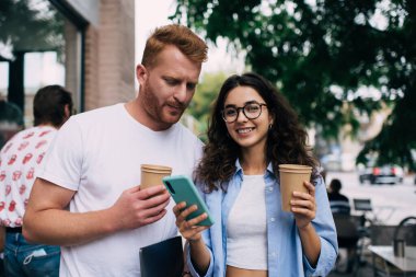 Gitmek için tek kullanımlık kahvesi olan neşeli beyaz kadın portresi ve kameraya gülümseyen modern akıllı telefon cihazı erkek arkadaşı ise cep telefonu pozu veren mutlu blog yazarı bildirimi aldı.
