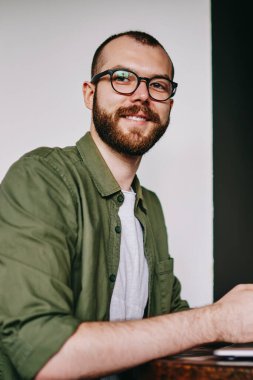 Yakışıklı hipster adam laptop, cep telefonu için sohbet ve paylaşım smartphone multimedya dosyaları ile netbook için bluetooth bağlantısı kullanarak tutan serbest meslek işten dikkati portresi