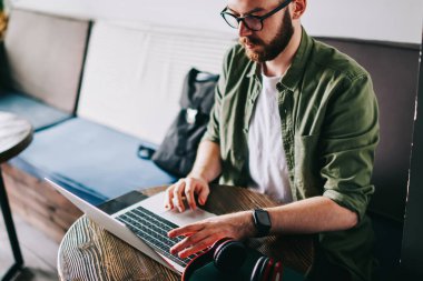 Genç tasarımcı yeni modern laptop kullanırken rahat öğrenci kafede oturan, hipster adam gözlük paylaşımında sosyal ağ ileti arkadaşlar profilinde, içerik çevrimiçi öğretici izlerken