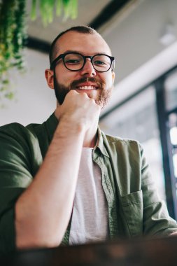 Yakışıklı genç bloger bekleyen arkadaş kafe ve yeni yayın oluşturma, sakallı iken cep telefonu elinde tutan ve sohbet hipster adam kamera seyir gözlük gülümseyen portresi