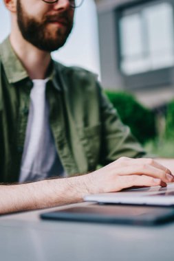 Yeni dizüstü bilgisayar, bilgi aramak ve serbest netbook açık havada üzerinde klavye üzerinde çalışan erkek programcı yazarak Sokak kafede oturan genç beyaz hipster biri kırpılmış görüntü