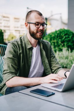 Genç hippi çocuk çevirmen tarafından internet, dil öğrenme en sevdiğim kafede yeni dizüstü bilgisayar kullanarak izlerken webinar online yolu ile modern aygıt dostum ve sosyal ağlarda takipçileri ile iletişim kurar.