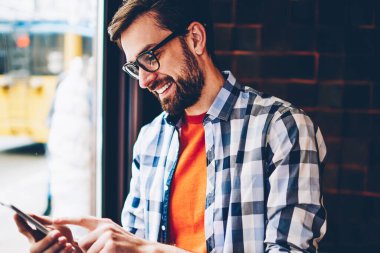 Tipik metin haber üstünde smartphone aygıt Eyewear neşeli hipster genç adam. Komik bildirim okuma ve sosyal ağlar üzerinde ücretsiz 4 g internet bağlantısı üzerinden telefon sohbet olumlu öğrenci