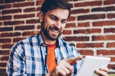 Başarılı sakallı genç adam rahat forması online sosyal ağlar üzerinden ücretsiz 4 g modern tablet sohbet metin bilgilerini yazarak giymiş Internet. Profil güncelleştirme olumlu hipster blogger