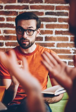 Ciddi optik gözlük alan coworking içinde toplantı sırasında arkadaşıyla tartışmaya genç adam sakallı. Birlikte laptop oturan ortak proje üzerinde meslektaşı ile strateji tartışmaya öğrenci