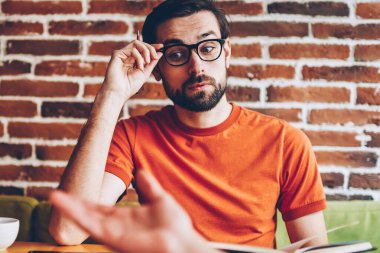 Planları ve coworking ortak başlangıç projesi geliştirmek için fikirleri tartışılması sırasında meslektaşım vizyon düzeltme uzakta iken dikkatle bakmak için şık gözlük hayran genç adam dinleme