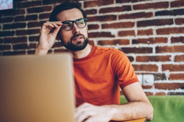 Düşünceli sakallı genç adam netbook, serbest çalışma bağlı 4 g için Internet süre uzağa bakıyor ve kendi yaratıcı fikirler geliştirmek düşünüyorum. Düşünceli blogger yayın üzerinde durulması