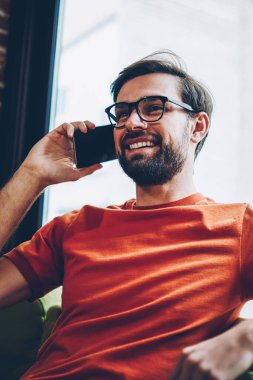 Sakallı smartphone aygıt üzerinde arama olumlu hipster adam arkadaşıyla görüşme ayarlamak için. Şık gözlük modern cep telefonu kafede oturan iç konuşurken neşeli genç adam