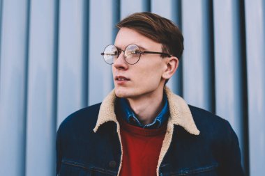 Uzak seyir vizyon düzeltme için şık gözlük yakışıklı hipster adam durulması. Düşünceli genç adam şık denim ceket ayakta açık havada kentsel ortamda giymiş. Düşünceli genç