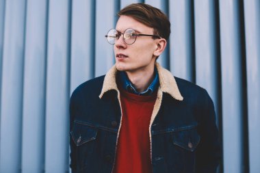 Uzak seyir vizyon düzeltme için şık gözlük yakışıklı hipster adam durulması. Düşünceli genç adam şık denim ceket ayakta açık havada kentsel ortamda giymiş. Düşünceli genç