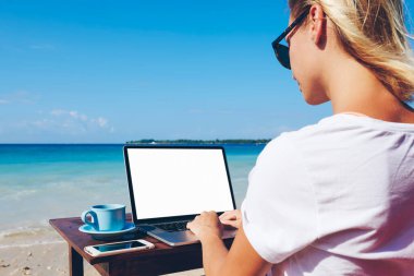 Yaratıcı kadın arkadan görünüm seyahat blogger ile güneşli gün yaz, tropikal adada uzak iş zevk millenial kadın freelancer okyanus plaj üzerinde oturan boş perde netbook yolu ile ağ