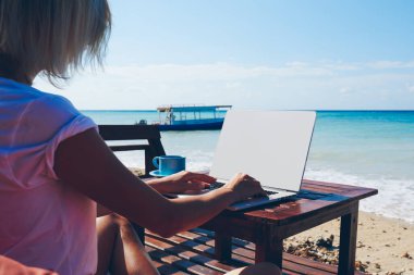 Yayın blogda okyanus plaj, denize yakın dizüstü kullanarak serbest iş iş kadının iyi kablosuz internet bağlantısı kullanarak ağ dizüstü bilgisayarı için klavye genç bin yıllık kız arkadan görünüm