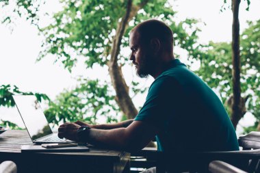 Düşünceli hippi, netbook aracılığıyla arkadaşıyla sohbet ediyor. Asya gezisi sırasında kafede oturuyor. Konsantre olmuş erkek serbest yazar, terasta dizüstü bilgisayar kullanarak ağlarda bilgi arıyor.