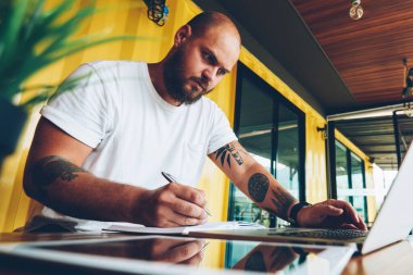 İnternet sitesi için yetenekli erkek blogcu eleştirileri dizüstü bilgisayarla bilgi analiz ediyor, internet üzerinden eğitim web sitesinde web sitesi izleyerek akıllı konsantre öğrenci öğreniyor.