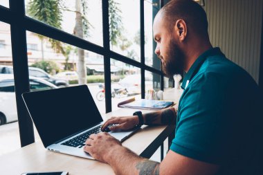 Ciddi genç adam netbook daktilo metni hakkında bilgi arıyor, yetenekli erkek klavye dizüstü bilgisayarda ve kafeteryada internet bağlantısı üzerinden internet sayfalarını tarıyor