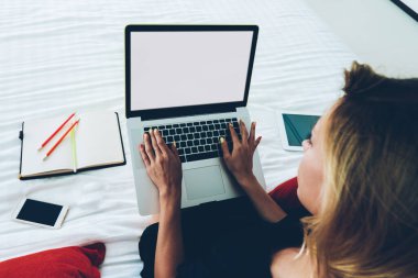 Dizüstü bilgisayarda çalışan ve rahat bir yatakta oturan serbest çalışan bir kadın klavyenin en iyi hayatı. Hippi kız evde mesai yapmak için blogda yazı yazmak için netbook kullanıyor.