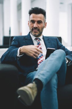 Formal giyim ofis iç dinlenme kendine güvenen olgunlaştı işadamı portresi giymiş. Akıllı gurur CEO'su 50 yaşında rahat koltukta otururken kameraya bakarak sakallı