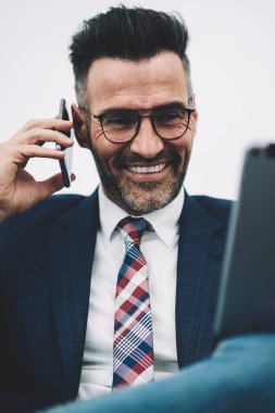 Neşeli olgun gurur CEO'su 50 yaşında dijital dokunmatik yüzey üzerinde komik bilgileri okuyun ve iş ortağı için smartphone üzerinde arama formal giyim giymiş. Cep telefonu üzerinde konuşurken mutlu Finans Müdürü