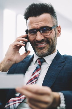 Müreffeh gurur CEO'su orta yarım uzunluk portre holding iş kartı elinde smartphone aygıtında çağrılırken yaşlı. Başarılı bir girişimci resmi modern cep telefonda konuşurken giymek